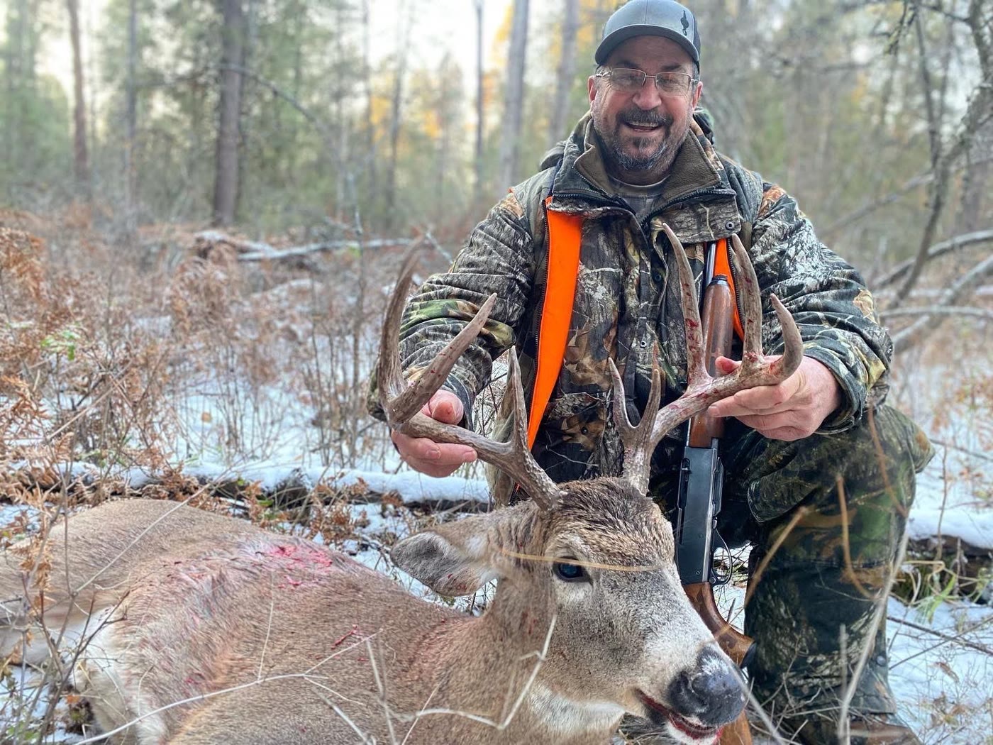 James McCormick kneeling in the snow with a big whitetail buck